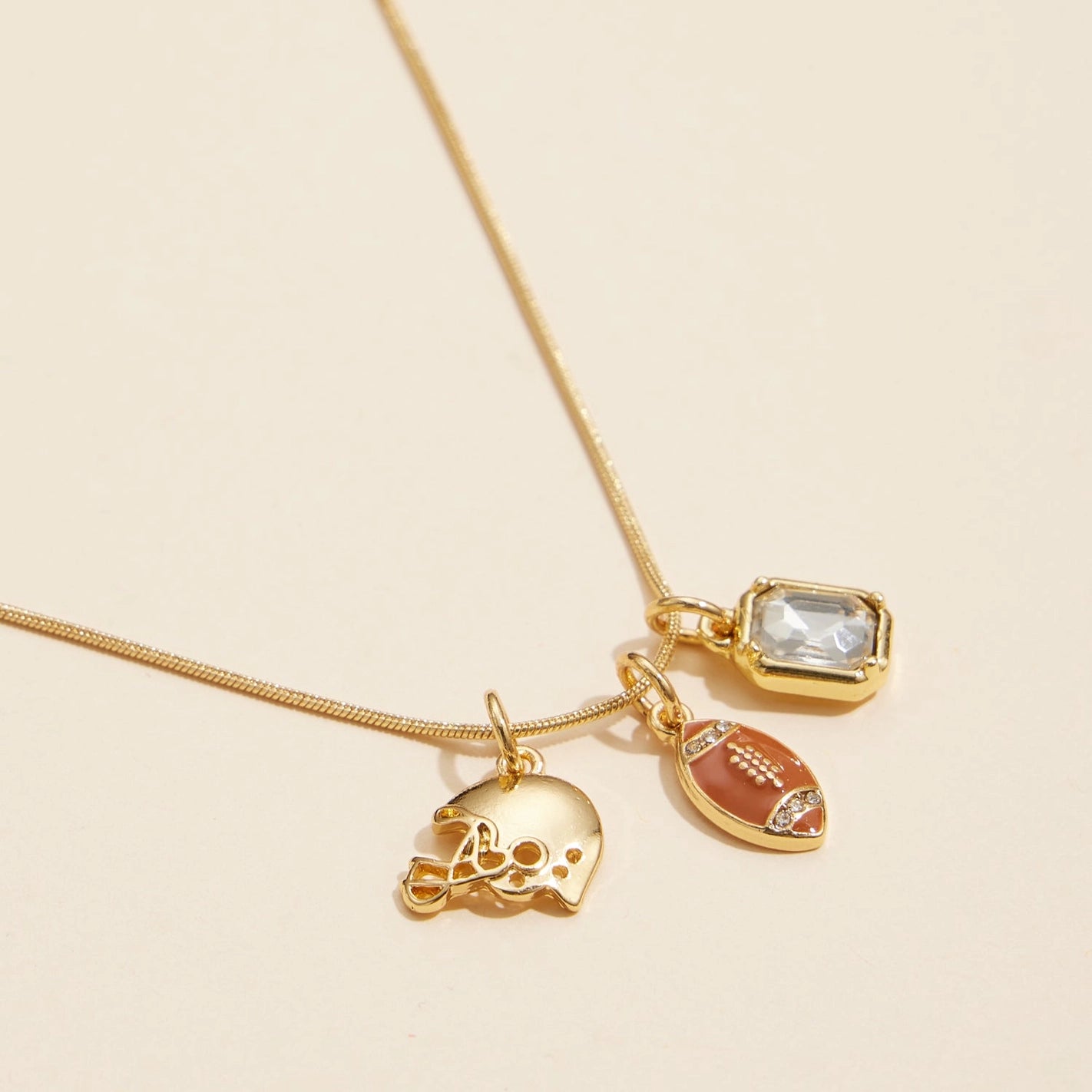 Close up view - Gold snake necklace with football, helmet and rectangle clear rhinestone charm