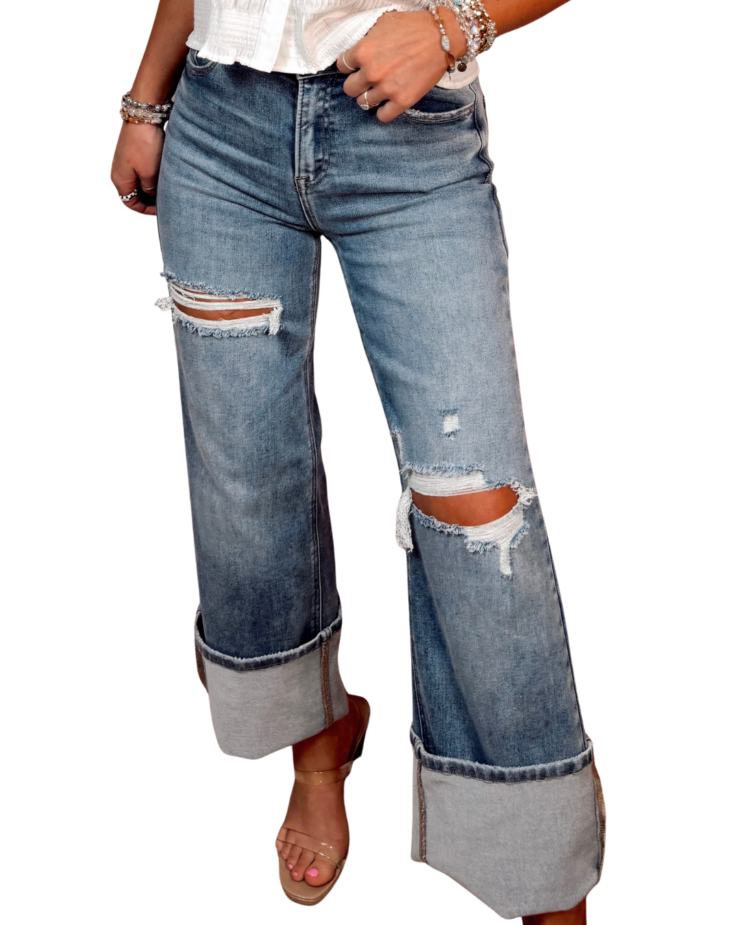 Ripped blue jeans shown cuffed worn by a person on a white background