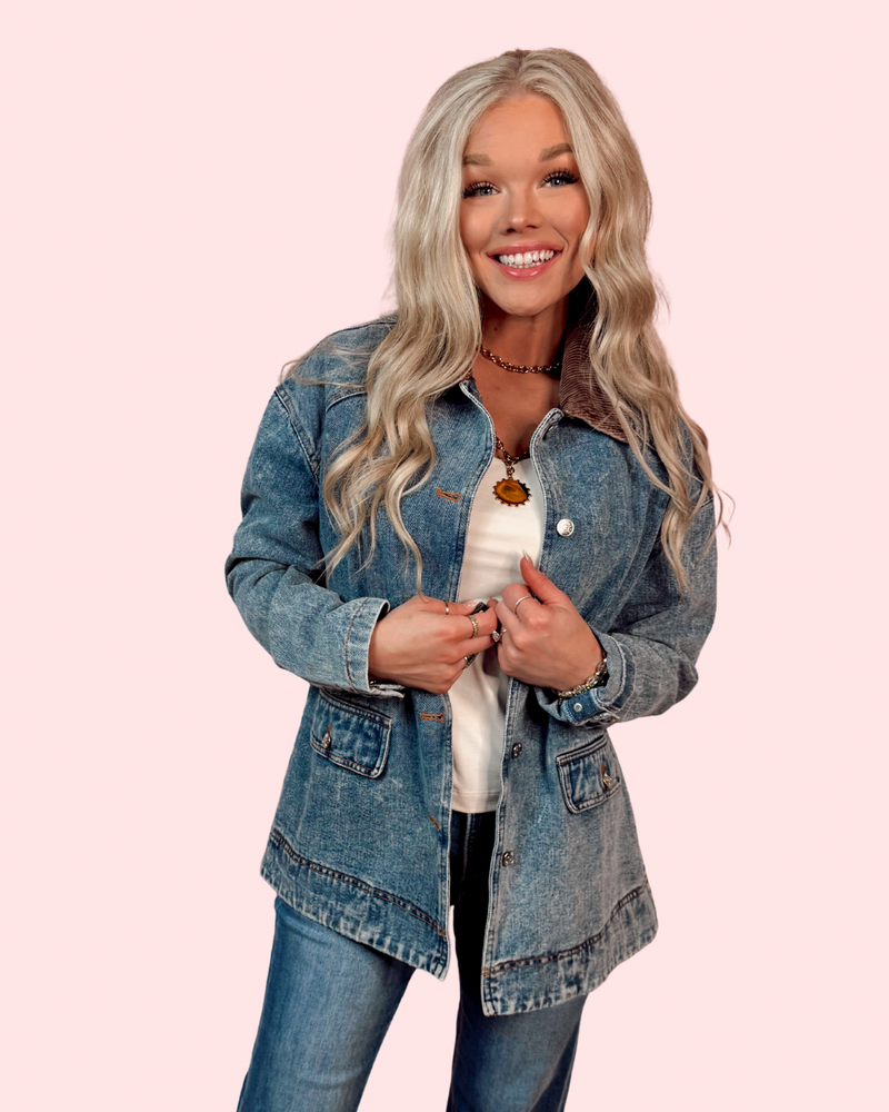 Woman wearing a denim barn jacket with courduroy collar on a pink background