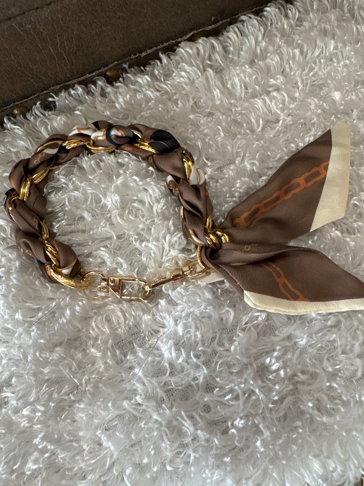 Bracelet/keychain/ phone holder with a brown silk fabric bow on a textured surface