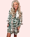 Woman wearing a long sleeve patterned dress on a light pink background