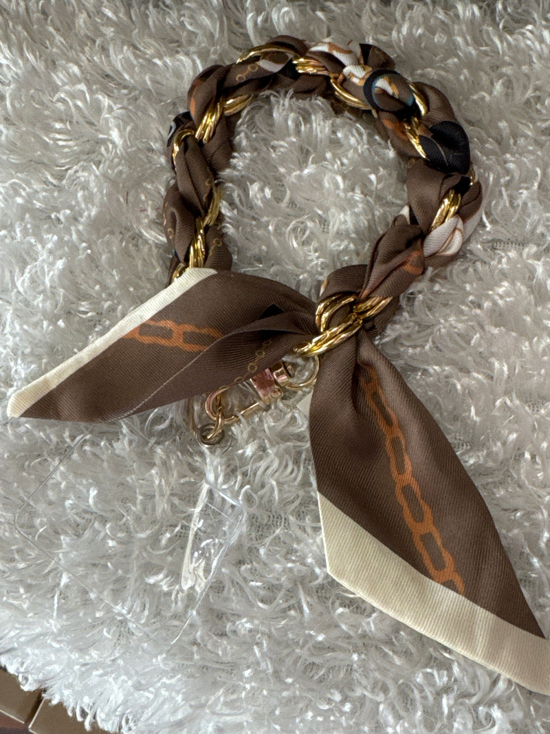 Bracelet with braided design and brown ribbon on a textured surface