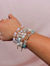 Close-up of a wrist wearing multiple beaded bracelets on a pink background