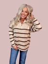 Woman wearing a striped sweater with 1/4 zippered neck and jeans on a pink background