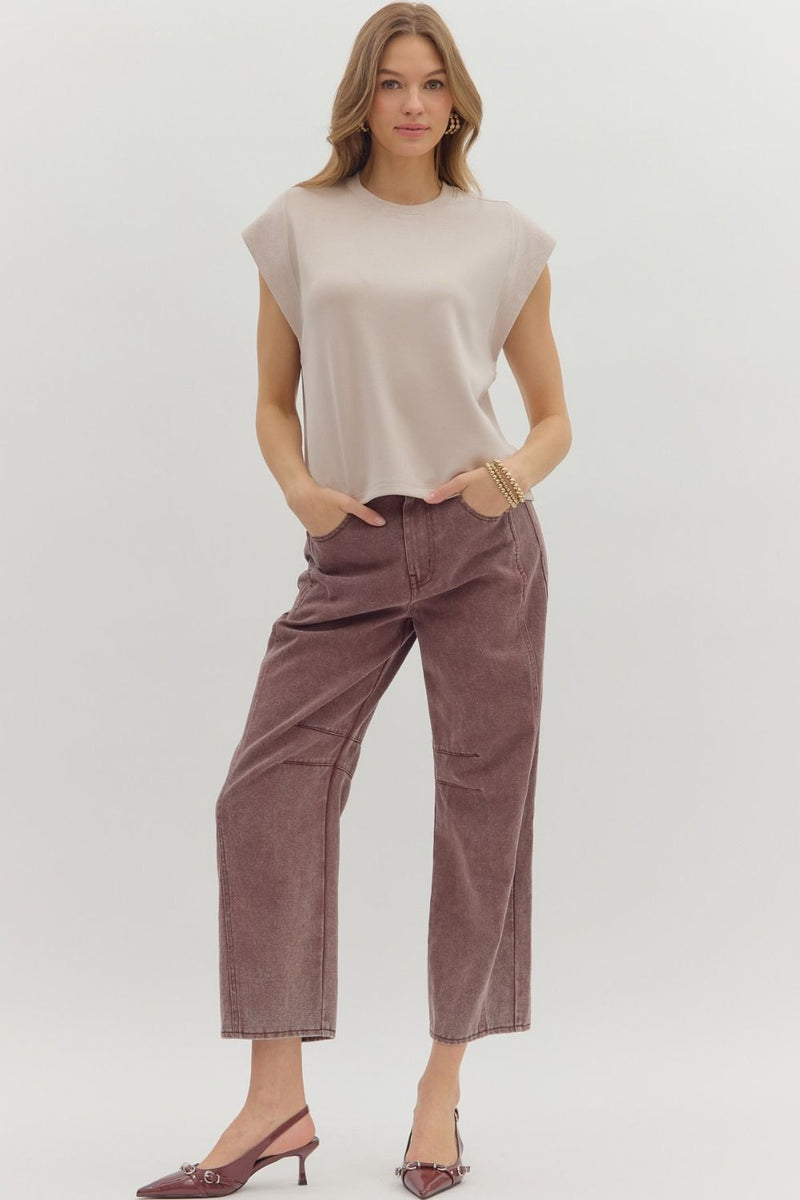 Woman wearing a beige sleeveless top and brown pants on a white background