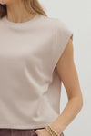 Beige sleeveless top worn by a woman on a plain background