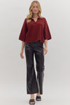Woman wearing slightly cropped ribbed 3/4 sleeve burgundy knit sweater and black pants on a white background