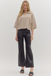 Woman wearing slightly cropped ribbed 3/4 sleeve beige knit sweater and black pants on a white background