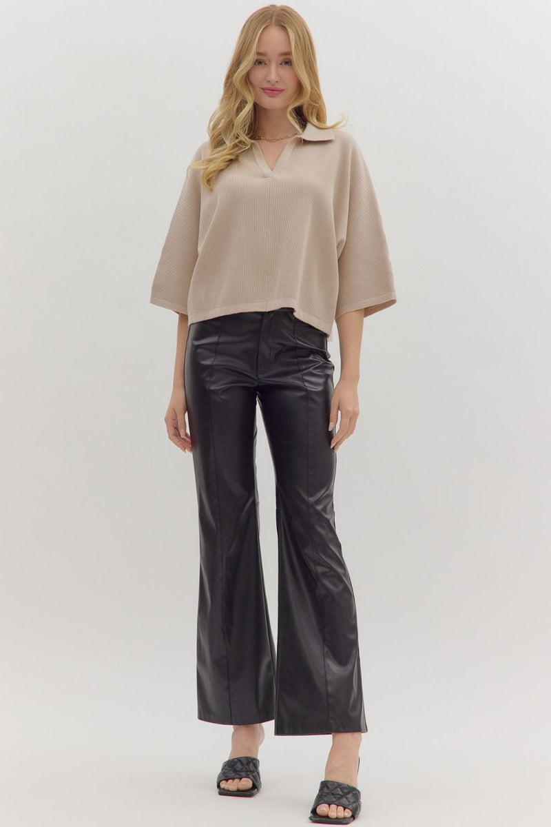Woman wearing slightly cropped ribbed 3/4 sleeve beige knit sweater and black pants on a white background