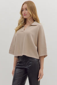 Woman wearing slightly cropped ribbed 3/4 sleeve beige knit sweater and black pants on a white background